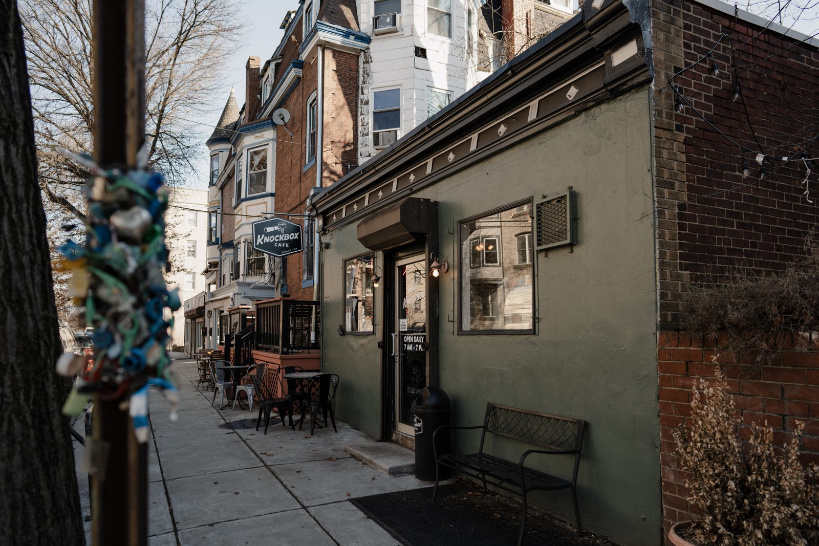 Knockbox Cafe's green storefront and sidewalk benches on S 45th St in Philadelphia
