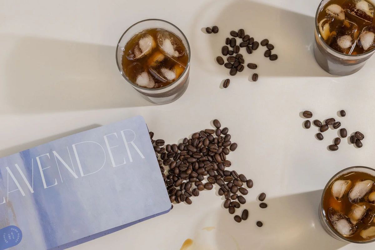 Iced coffees and scattered coffee beans beside a Lavender Coffee Boutique bag