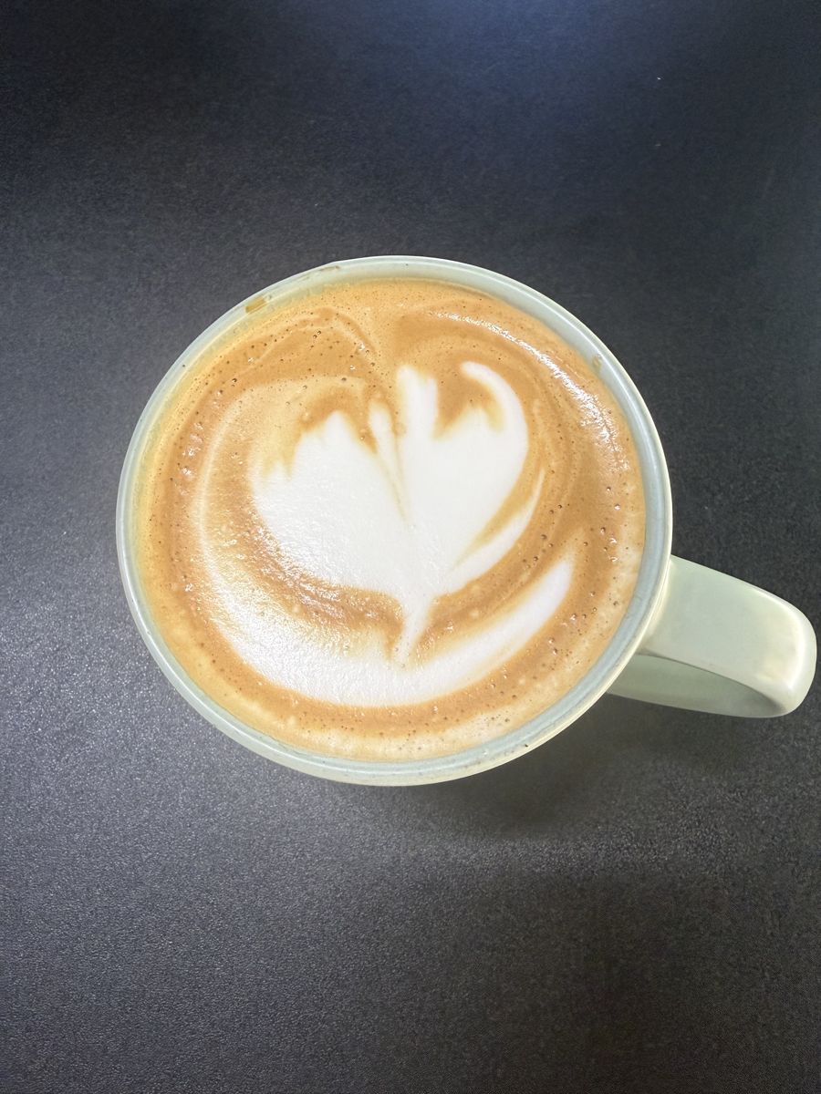 Overhead view of Compass Point’s Brown Butter Latte with latte art in a pale green mug
